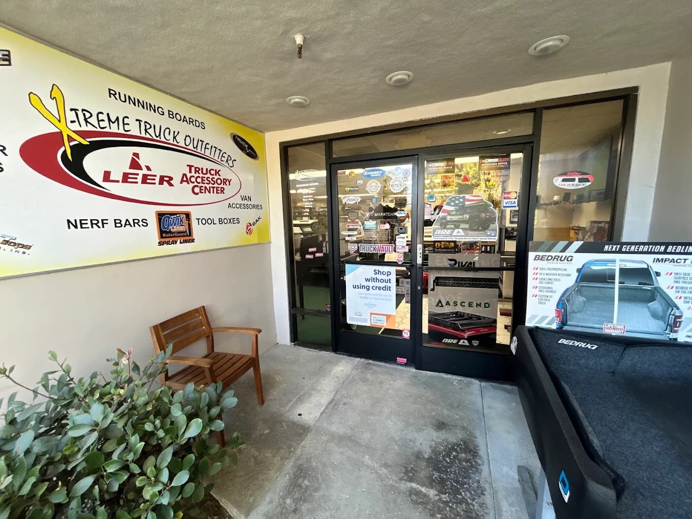 Storefront entrance under the Xtreme Truck Outfitters and LEER Truck Accessory Center sign, with a BedRug display outside