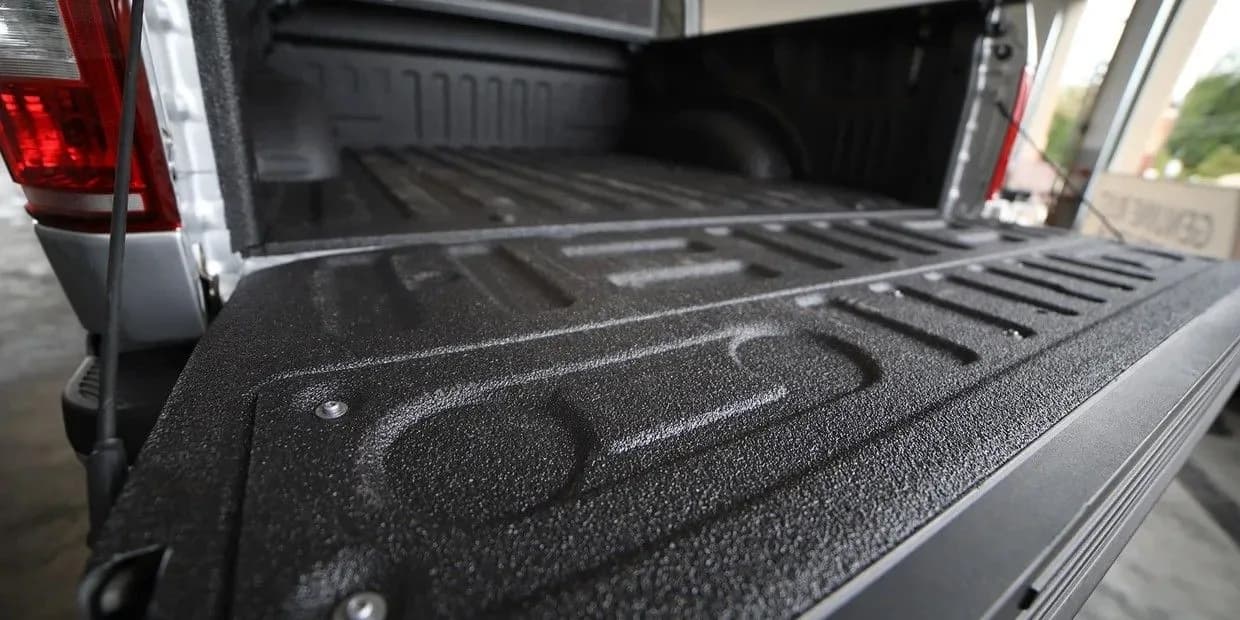 Close-up of a textured spray-in bed liner over a truck bed rail and tailgate